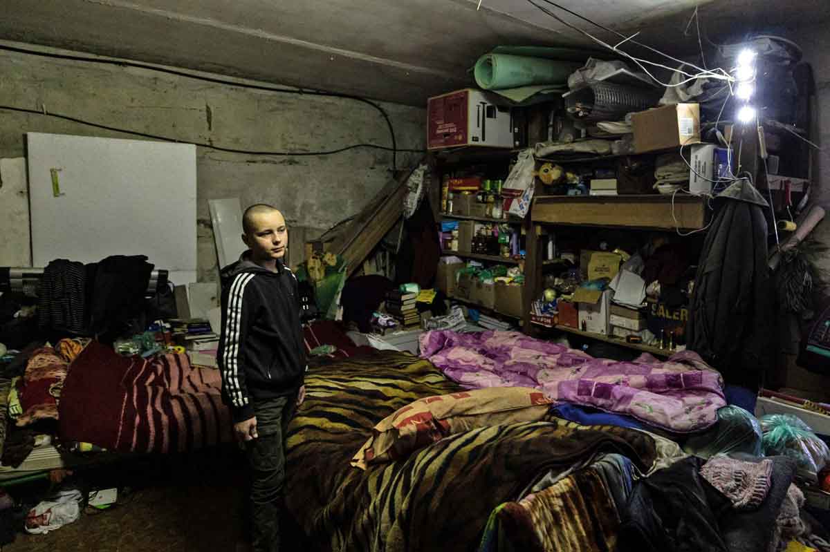Gleb Petrov, 14 Jahre alt, am 21. Dezember 2022 mit seiner Familie in einem Keller in der Stadt Bachmut in der Ostukraine. (Foto von Sameer Al-DOUMY / AFP)