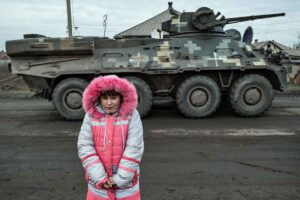 Lisa Shtanko, 8 Jahre alt, sieht zu, wie ein Militärfahrzeug am 23. Dezember 2022 vor ihrem Haus in der Stadt Lyman in der Ostukraine vorbeifährt. (Foto von Ionut IORDACHESCU / AFP)
