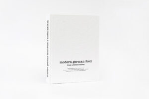 Das Buch erschließt die Welt der regionalen, saisonalen und zeitgenössischen Küche Deutschlands. Kit Schulte setzt sich mit kulinarischen Traditionen und handwerklichen Methoden auseinander und verbindet kulinarische Vergangenheit mit der Wiederentdeckung traditioneller Gerichte und vergessenen Geschmack bis zur Gegenwart mit zeitgenössischen Trends wie Wildes sammeln. Mit dem Schwerpunkt auf Gemüse und Kräutern interpretiert sie traditionelle, fleisch- und milchlastige Rezepte neu, um sie in frische, gesündere Gerichte zu verwandeln, die oft mit gesammelten Wildpflanzen und Wildkräutern verfeinert werden. Der Leser wird inspiriert, einen neuen Zugang zum Kochen zu entdecken und mit wilden Aromen und Rezepten zu experimentieren. Das Buch wurde mit Blick auf ein englischsprachiges Publikum geschrieben und richtet sich an jeden, der sich für diese innovative, frische Herangehensweise an die deutsche Küche interessiert, sei es als gelegentlicher Besucher oder als kürzlich zugezogener oder dauerhaft in Deutschland lebender Mensch. Die meisten englischen Kochbücher über die deutsche Küche neigen dazu, die stereotypische Vorstellung zu betonen, dass deutsches Essen ausschließlich aus Schnitzel, Sauerkraut, Bratwurst, Spätzle usw. besteht. Heutzutage sehen wir jedoch, vor allem in Städten und urbanen Gebieten, einen allgemeinen Trend zu gesünderen, frischeren und moderneren Küche, die eine Vielzahl von nachhaltigen und gesunden Zutaten verwendet. Die Kapitel enthalten eine Einführung in die kulinarischen Regionen Deutschlands und informative Texte zur Esskultur. Die Rezepte sind unterteilt in Vorspeisen, Suppen, Salate, eine kleine Fleisch- und Fischauswahl, Kuchen, Desserts sowie eine Zusammenfassung von deutschen Festtage und kulinarischen Traditionen. Das Kapitel "Von Feldern, Bäumen und Wiesen" ist wie ein Lexikon aufgebaut, wunderschön illustriert von der Biologin und Künstlerin Claire Cook. Es vermittelt botanische und kulinarische Informationen über Gemüse, Obst und gesammelten Wildpflanzen, die in der deutschen Küche verwendet werden. Nora Novak, eine Fotografin aus Berlin mit großer Erfahrung in der Food-Fotografie, ist für den Großteil der inspirierenden Bilder verantwortlich. Die Bilder sind alle ohne den Einsatz von Sprays, Plastik etc. aufgenommen, natürlich fotografiert und kommen direkt aus der Küche.